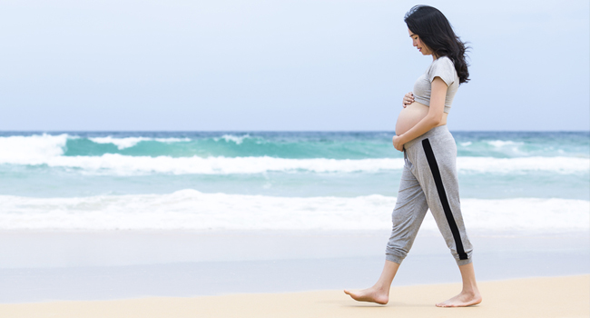 Pregnant Woman walking on the beach